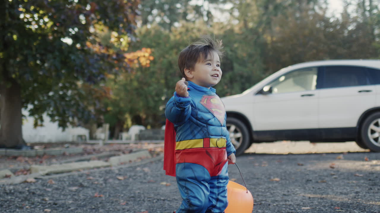 un niño vestido como un superhéroe con una canasta de dulces en forma de calabaza. día de halloween