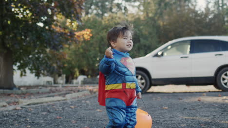 A-child-dressed-as-a-superhero-with-a-candy-basket-in-the-form-of-a-pumpkin.-Halloween-Day
