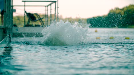 Close-up-shot-of-Caucasian-kid-jumping-from-the-pier-into-the-lake