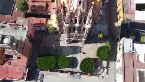 San-Miguel-De-Allende-Mit-Seiner-Ikonischen-Rosa-Kirche-Und-Dem-üppig-Grünen-Platz,-Luftaufnahme