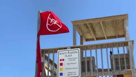 a no swimming flag flies from a lifeguard stand at the beach