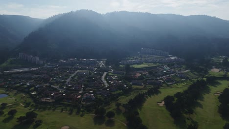 aerial view of residential buildings in playa grande, quintay, surrounded by lush greenery and rolling hills in chile. dolly, tilt up
