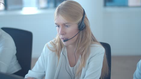 serious fair haired operator in headset taking call