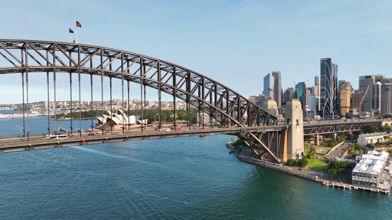 barrido aéreo cinematográfico del puente del puerto de sídney para revelar la ópera de sídney al atardecer, australia