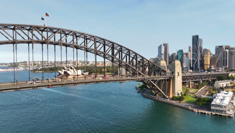 cinematic aerial sweep of sydney harbour bridge to reveal sydney opera house at sunset, australia