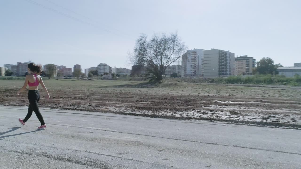 비포장 도로를 걷는 젊은 brunnete 피트니스 여성의 회전 와이드 샷