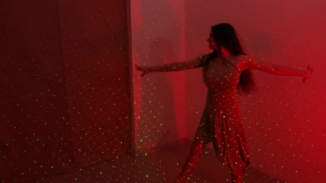 Charming-slim-Caucasian-woman-practicing-a-dance-in-a-white-room-with-red-lights-and-lasers