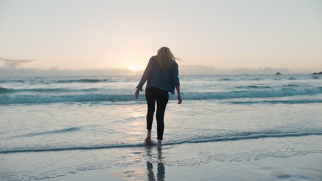 Junge-Frau-Allein-Am-Strand,-Blick-Auf-Den-Sonnenuntergang-Am-Meereshorizont,-Denkt-An-Eine-Reise,-Denkt-über-Das-Leben-Nach-Und-Genießt-Die-Freiheit-Eines-Friedlichen-Sommerurlaubs