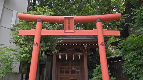 a prominent red torii gate marks the entrance to kuramae shrine, a traditional japanese spiritual site nestled amidst urban surroundings.