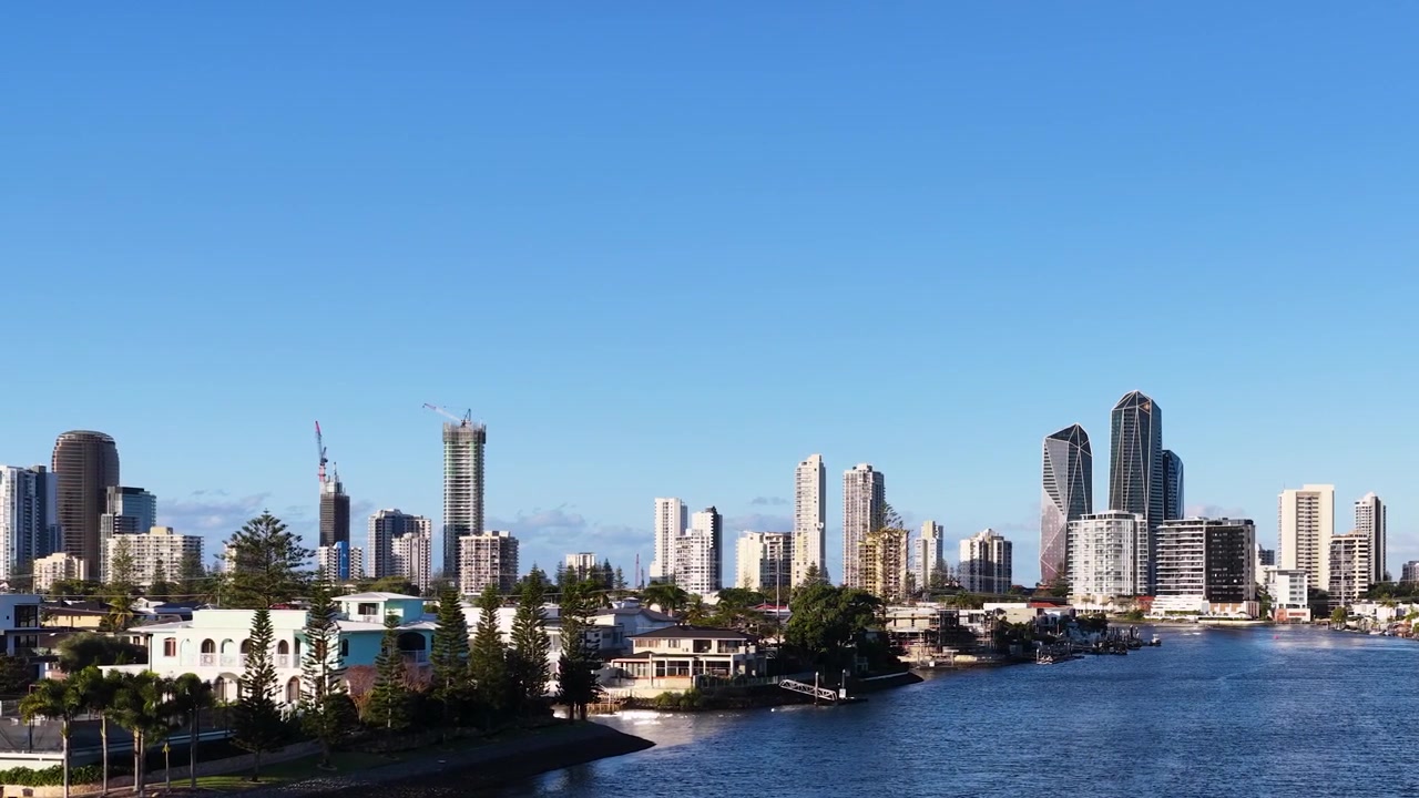 Lenta panoramica della telecamera attraverso lo skyline di una città costiera con case sul lungomare e acqua blu del fiume.