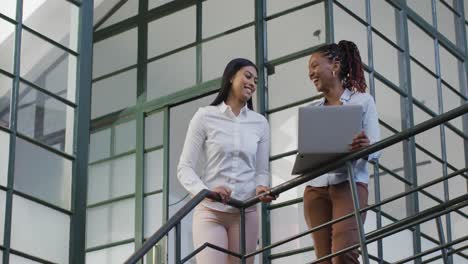 happy diverse female business colleagues using laptop discussing work at office