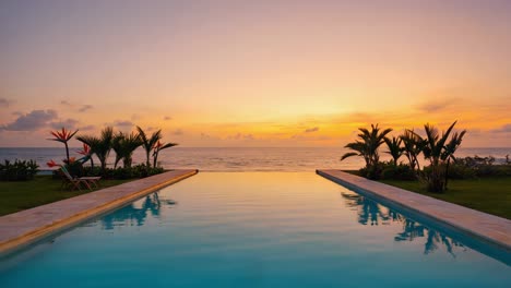 tranquil scene of an infinity pool reflecting the vibrant colors of a beautiful sunset over the ocean, with lush greenery and palm trees creating a luxurious and relaxing atmosphere