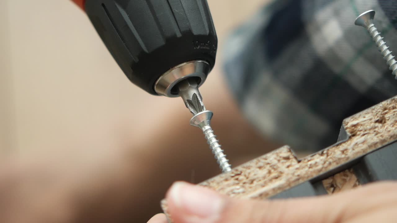 Using a power drill to install screws in wood