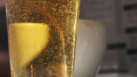 golden beer in glass, close-up slow motion in sunlit bar