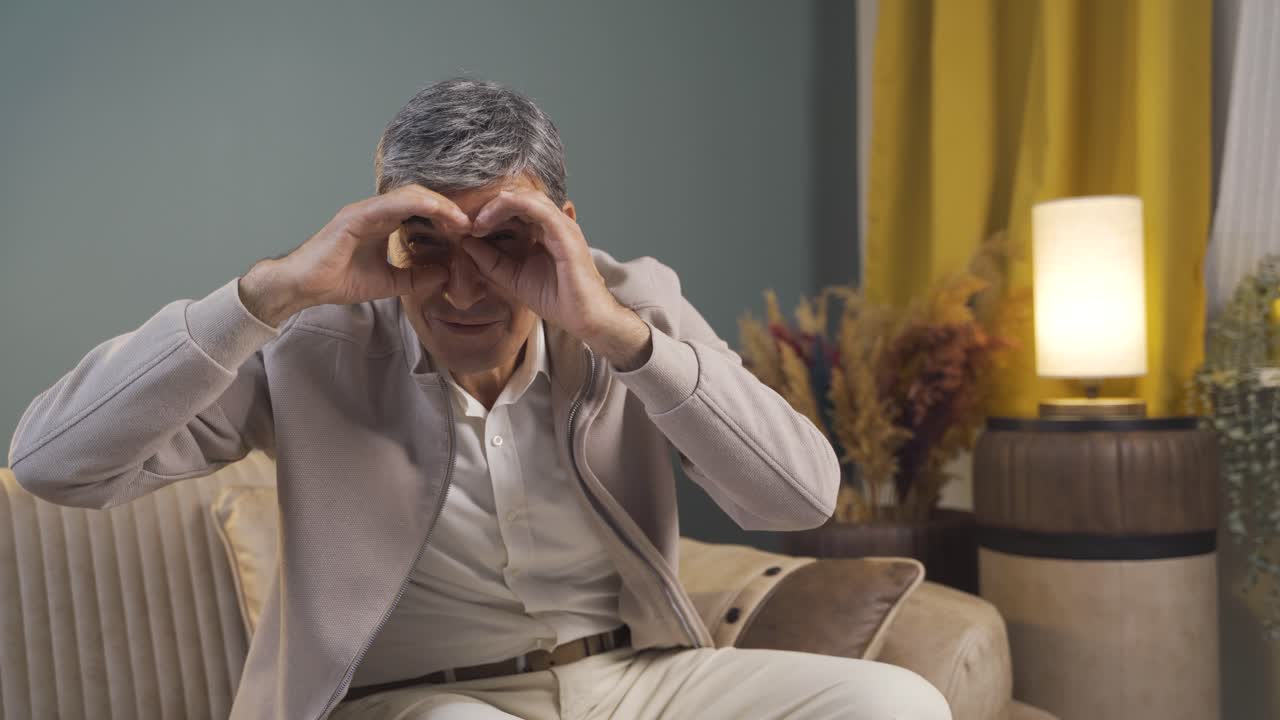 un anciano con binoculares mirando hacia otro lado.