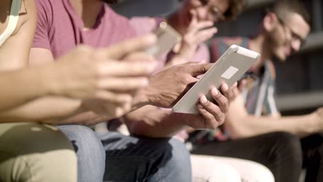 people sitting on wooden bench and using digital devices