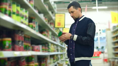 man shopping for canned goods in a grocery store