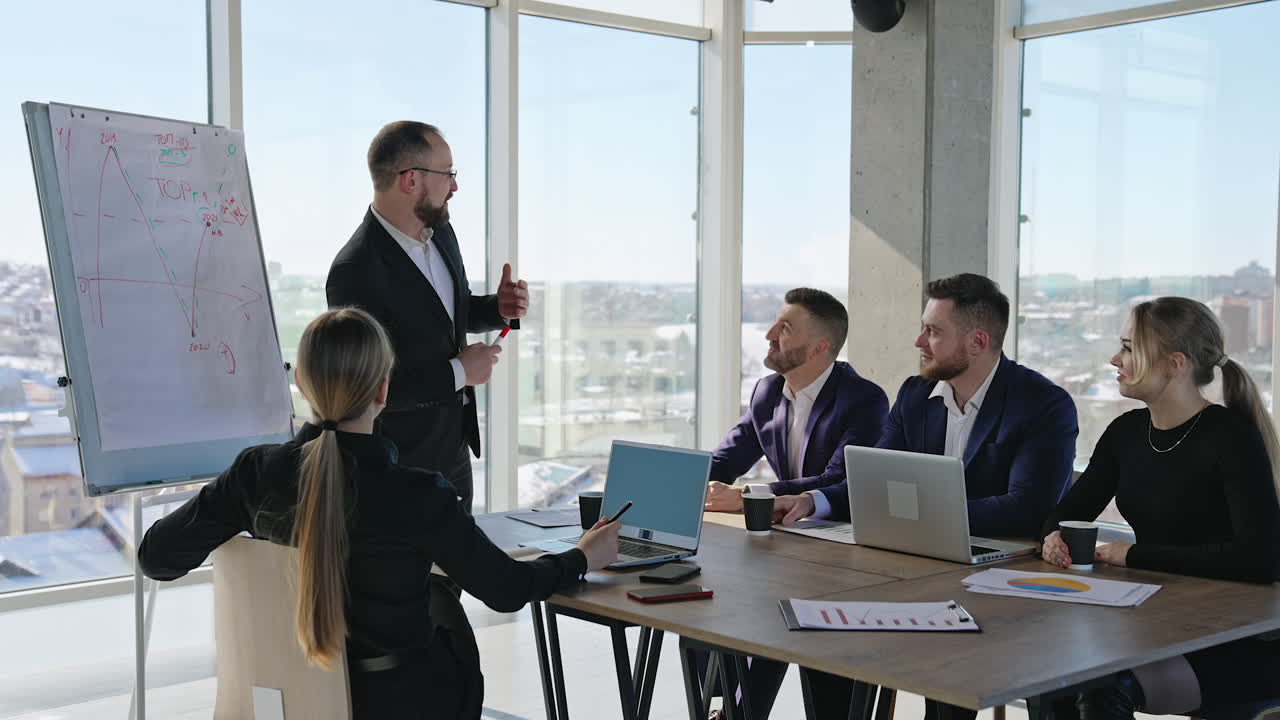 Colleagues are having meeting in sunlit office. Friendly communication and building strategies in the office team. City at the backdrop.