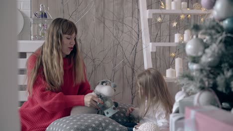 young-woman-in-red-sweater-nurses-little-girl-in-bedroom