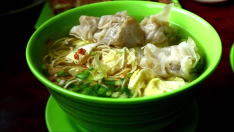 close up handheld video shot of freshly cooked wanton noodle soup in a bowl