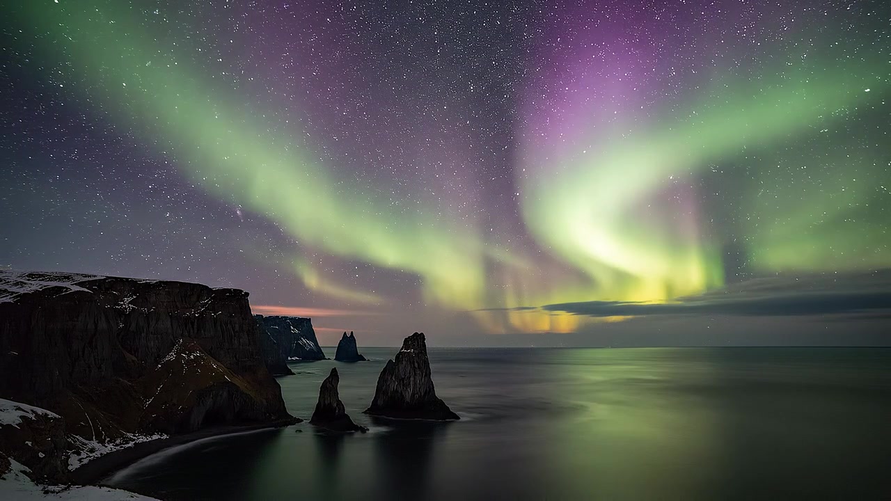 Splendida Aurora Boreale su formazioni rocciose costiere di notte.