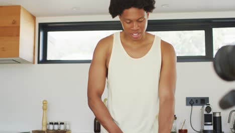 Fit-african-american-man-cooking,preparing-smoothie-and-filming-vlog