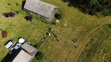 hacienda rural recreativa con gente jugando voleibol en una cancha de césped verde, vista de órbita aérea