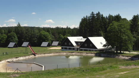 a luxury chalet and small cabins near a swimming pond at a beautiful resort, czech republic, aerial