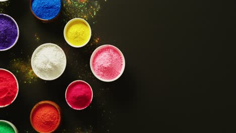 video of multi coloured powder in bowls with copy space on black background