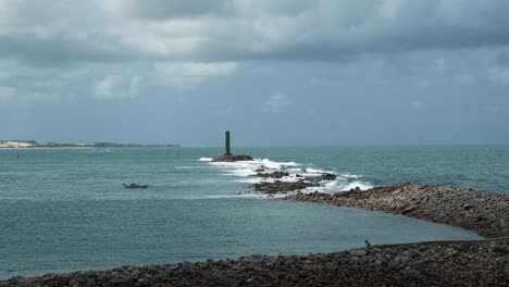 Waves-crashing-into-a-man-made-wave-breaking-peninsula-leading-to-the-small-lighthouse-of-the-Three-Wise-Men-in-the-topical-capital-coastal-city-of-Natal-in-Rio-Grande-do-Norte,-Brazil-on-a-summer-day