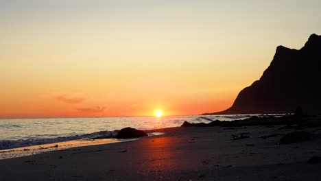 Waves-rolling-in-from-the-sea-at-Uttakleiv-beach-during-the-midnight-sun-in-Lofoten,-Norway