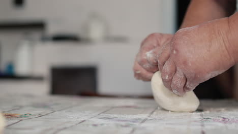 una anciana amasa la masa junto a una vieja estufa de leña