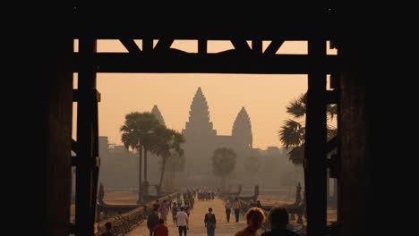tourists wander through a stunning temple doorway, capturing the beauty of angkor wat illuminated by the soft morning light. the serene atmosphere enhances their exploration and experience.