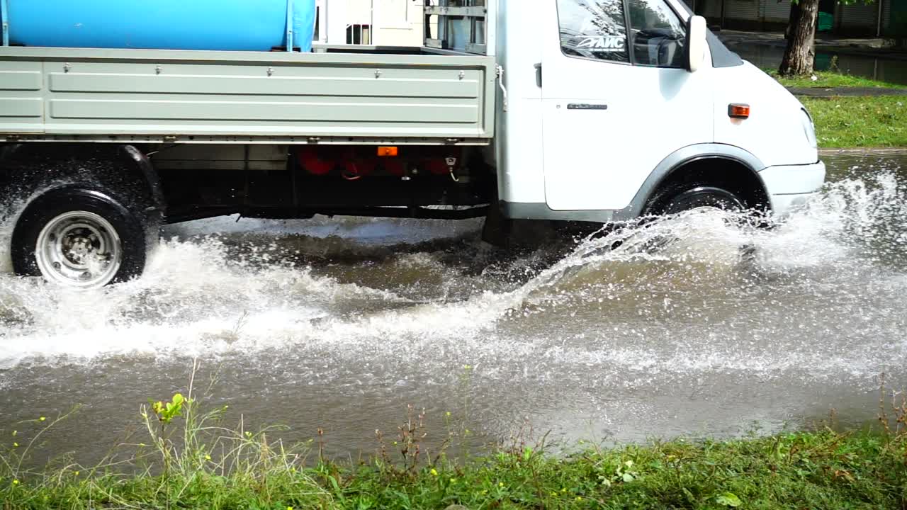 Inundação na cidade depois de uma chuva. Carros se movem pela rua. Câmera lenta