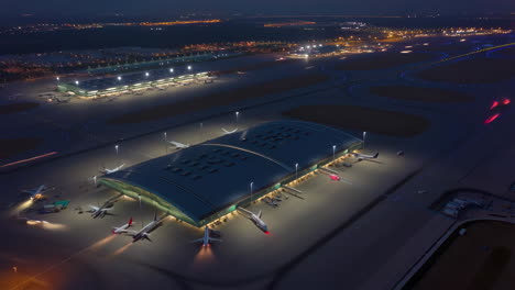 aerial night view of a modern airport terminal with parked airplanes