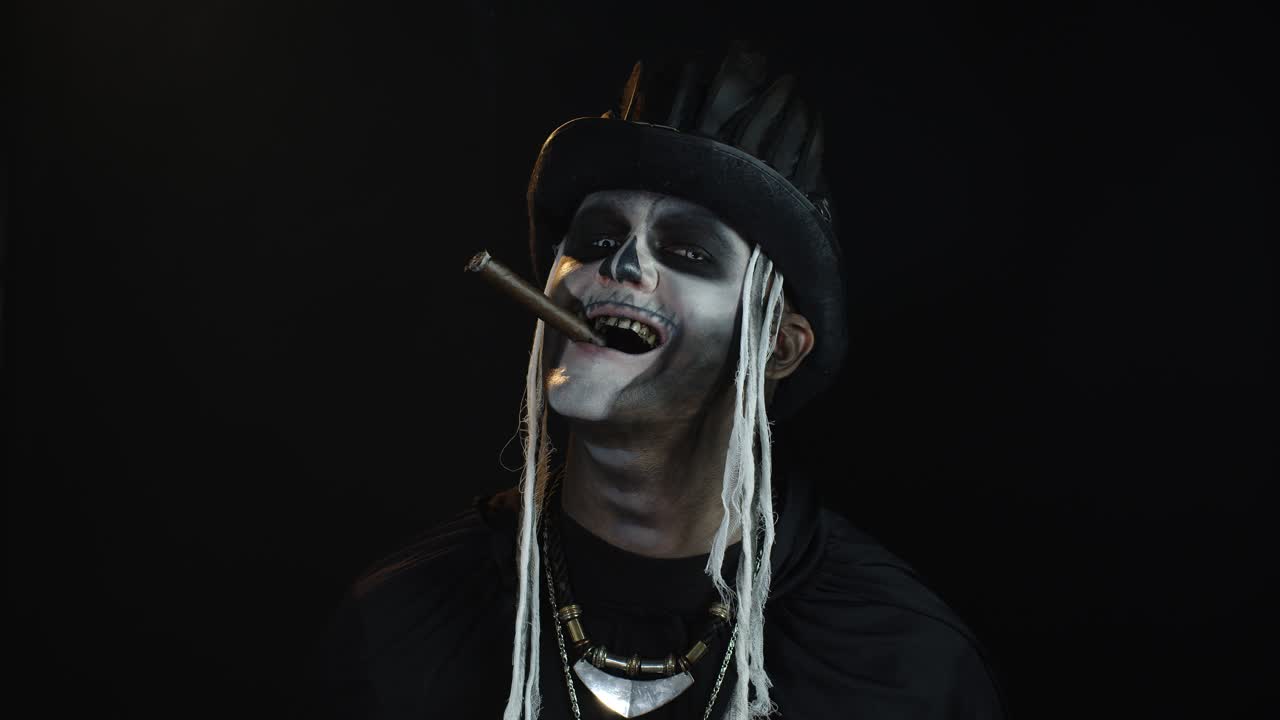 Skremmende mann i et Halloween-skjelett cosplay-kostyme røyker sigar, lager grimaser, smiler.