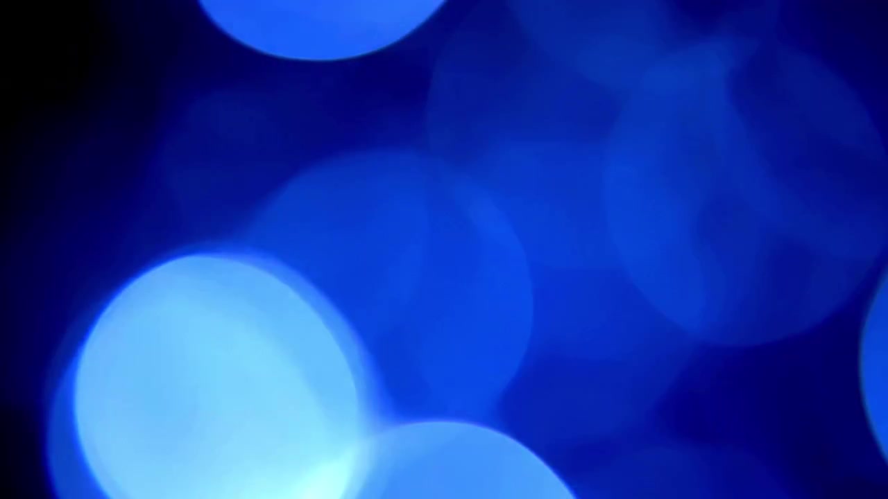 Sfere di luce bokeh blu astratte su sfondo nero.