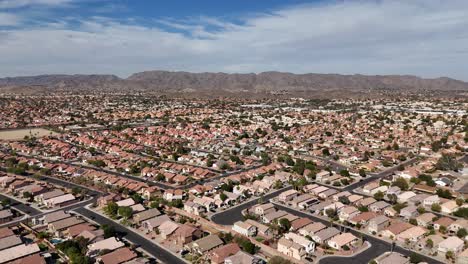 aerial view of suburbs in arizona, hundreds of family homes with mountain range and blue sky in background