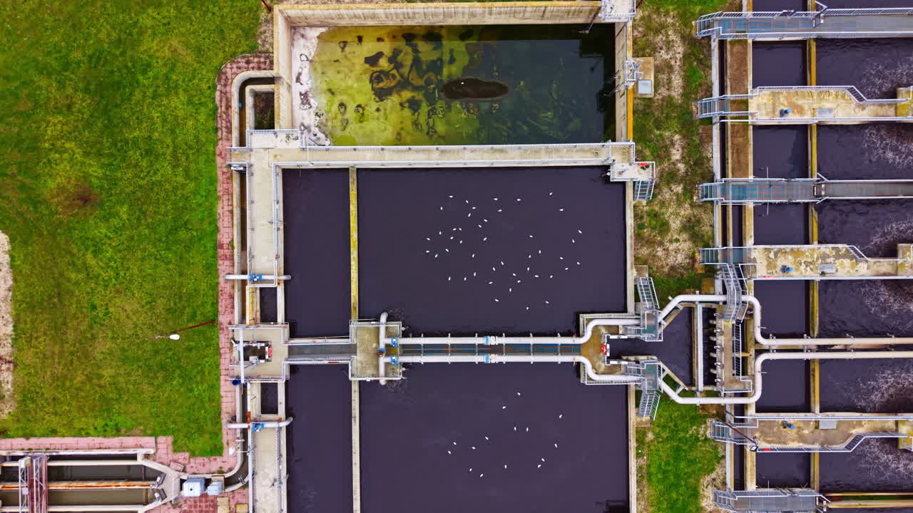 Water treatment facility processes wastewater with treatment tanks and channels at a city location during daytime hours