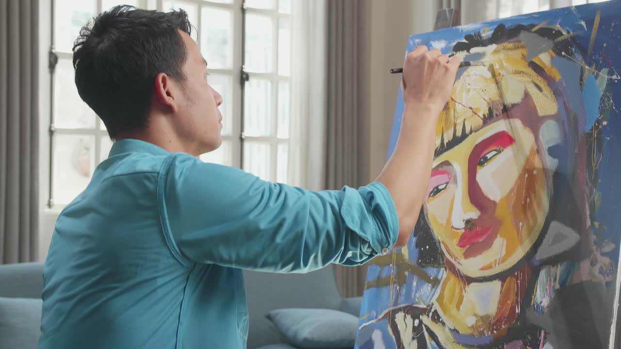 Side View Of An Asian Artist Man In Wheelchair Holding Paintbrush Mixed Colour Thinking And Painting A Girl On The Canvas