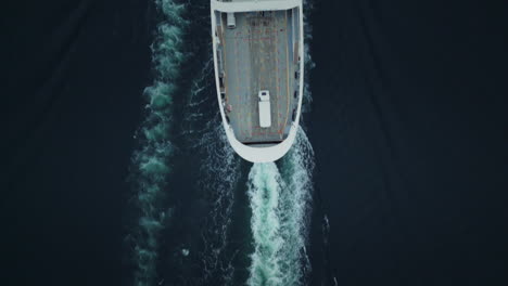 top-down shot overhead a ferry travelling with cargo onboard creating waves