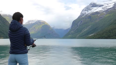 mujer pescando en una caña de pescar girando en noruega.