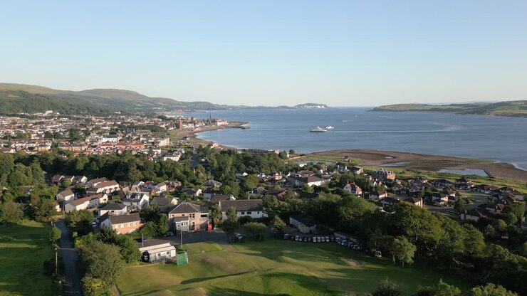 Aerial rise over Largs town houses and coastline in Scotland, UK