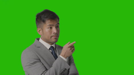 portrait of serious businessman in suit thinking against green screen