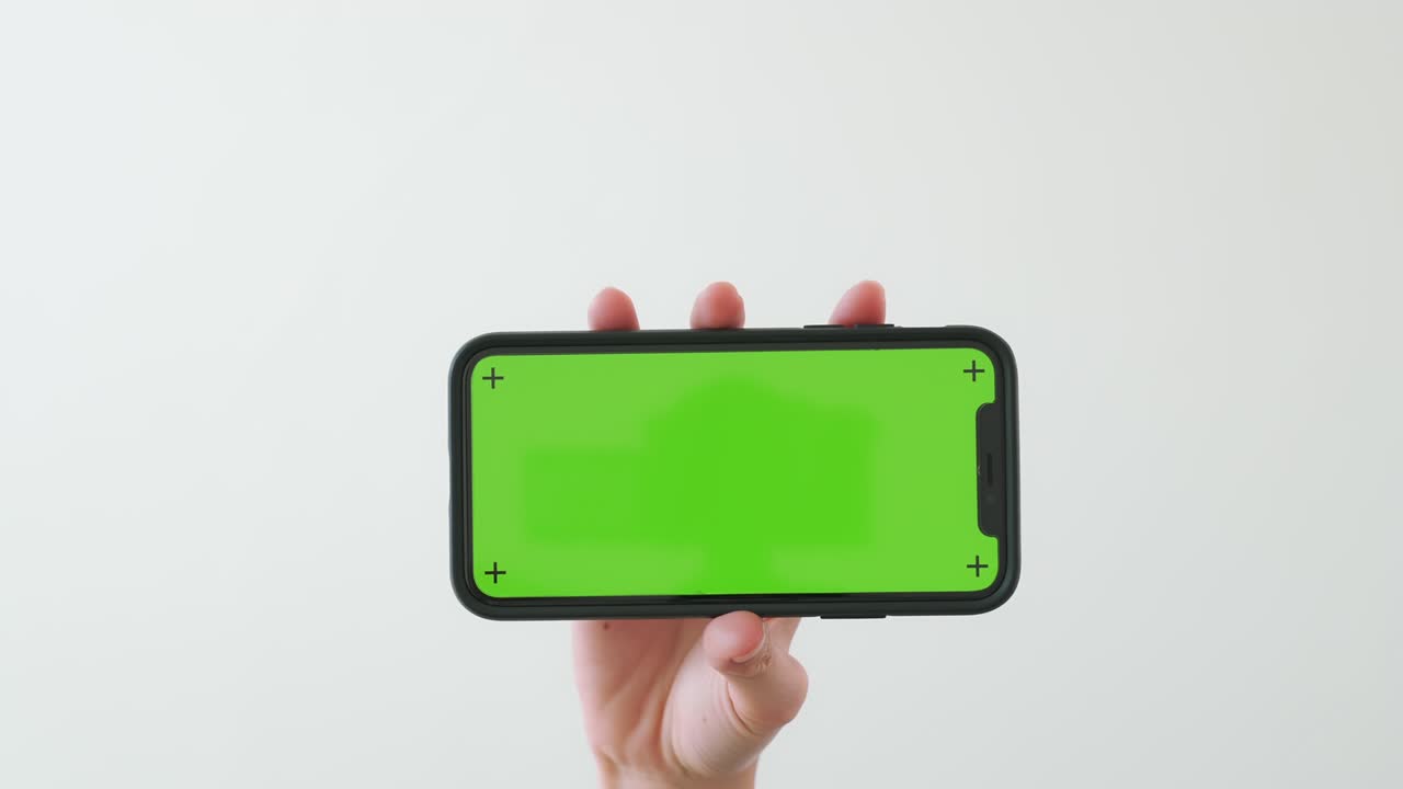 크로마 키 스크린과 색 배경에 표시된 스마트폰을 손으로 들고 있습니다.