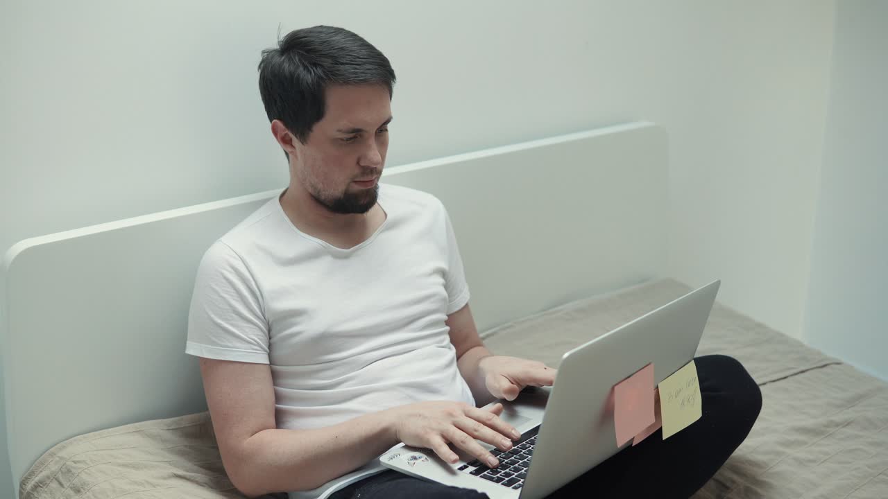 침대에 노트북으로 일하는 남자