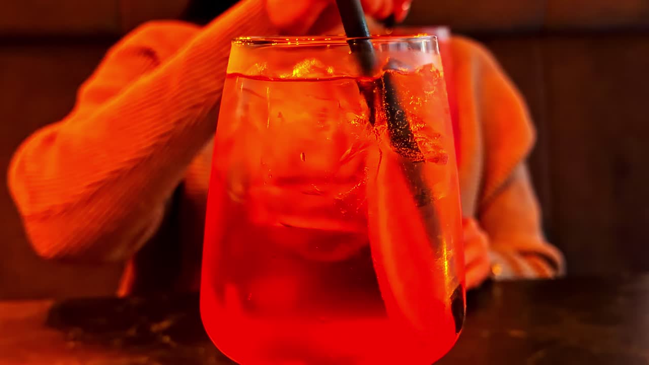Primo piano di un long drink su un tavolo da bar durante un appuntamento con una donna sullo sfondo