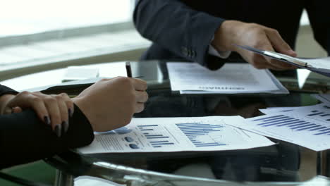 Close-Up-View-Of-Business-People-Holding-Documents-On-A-Table