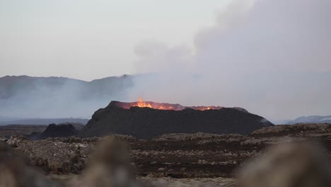 Wide-shot-of-Litli-Hrutur-Volcano-exploding-and-spewing-lava-during-eruption-with-rising-smoke-in-Reykjanes,-Iceland