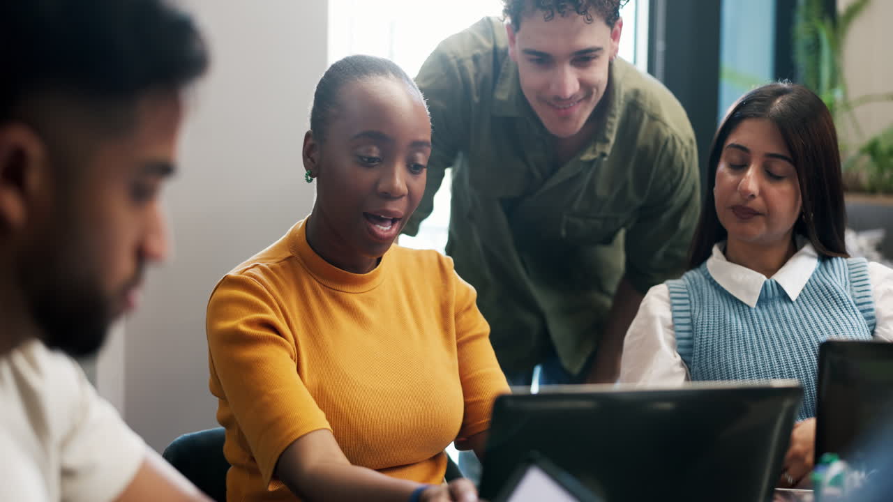 Diverse Group of Young Professionals Collaborating on Laptop in Modern Office